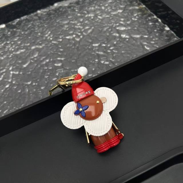 Vivienne Xmas包饰以牛皮革和耀目金属烘托年底节庆气氛，为Monogram风格吉祥物Vivienne戴上配有绒球的针织帽，犹如平安夜踏雪而至的，谐趣设