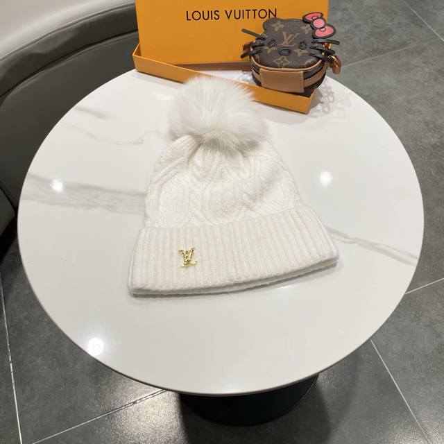 毛线帽经典麻花编织设计，帽身配有金色Lv标志。配狐狸毛球帽子采用优质羊毛+兔毛针织面料，保暖舒适，帽顶配有同色系毛球装饰，时尚大方。 帽子细节： - 经典麻花编