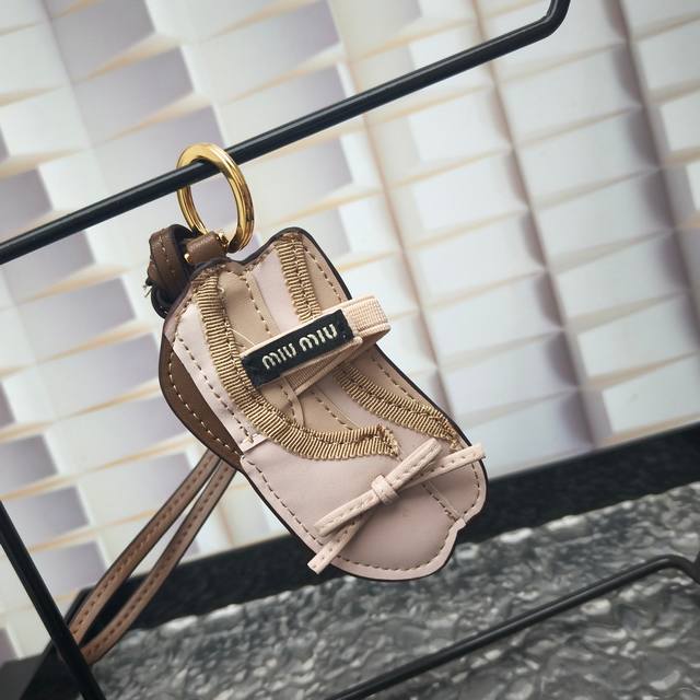 p90-牛皮革钥匙扣挂饰 Miu Miu 衣柜中的独特元素变身为手袋的珍贵配饰，实现俏皮而个性的组合。这款挂饰的灵感来自著名的 Miu 芭蕾舞鞋，的设计增添了独