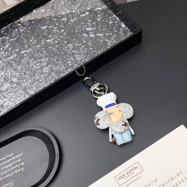 Vivienne Baker 收藏版包 M01467 Vivienne 形象戴上路易威登标识厨师帽、手持擀面杖，并为 Monogram 皮革花瓣沾上巧克力，令品