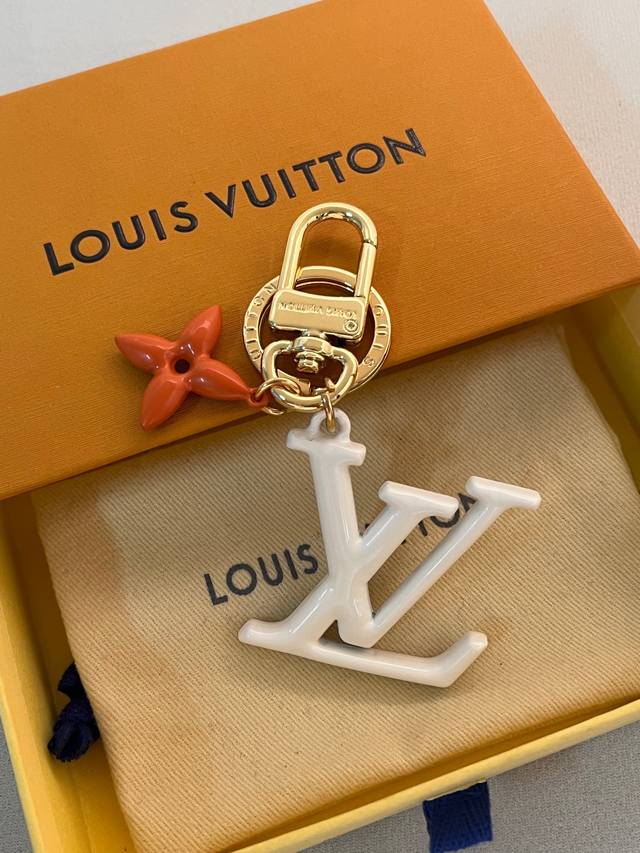 Lv Pop Flower包和钥匙圈的魅力非常适合为皮革配饰增添标志性的色彩，其特点是金色金属钩环，点缀着充满活力的Lv首字母和会标花吊坠符咒花押和首字母Lv