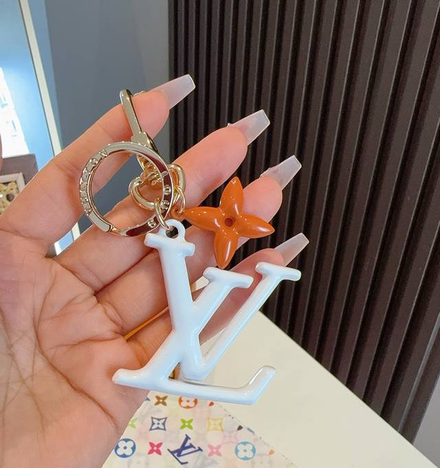 lv钥匙扣珐琅工艺Lv字母挂件 Pop Flower包和钥匙扣的魅力非常适合为皮革配饰增添标志性的色彩，其特点是金色金属钩环，点缀着充满活力的Lv首字母和会标花