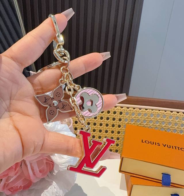 Lv 钥匙扣包挂件 Spring Street Chain 包饰将 Monogram 花卉和 Lv 字母等经典元素化为袖珍挂饰，在淡雅色彩和 Monogram