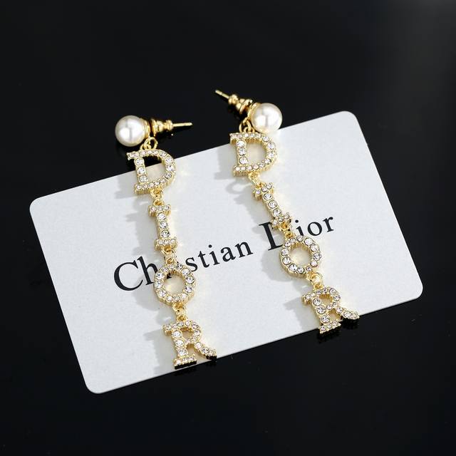 迪奥珍珠耳环 这款 Dior Tribales 耳环在 Dior 标志性款式的基础上演绎出新的风格。白色树脂珠饰悬挂着银色饰面金属字母“D.I.O.R.”，字母