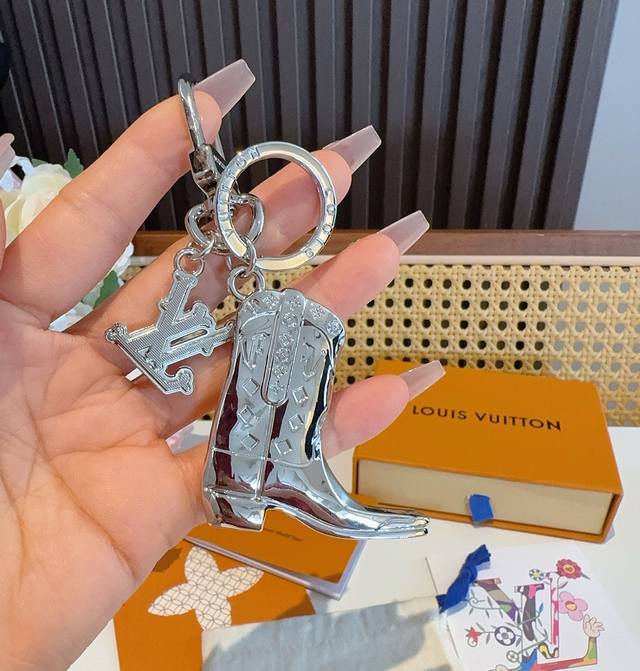 Lv钥匙扣 靴子挂件车钥匙挂饰，品牌经典标识巧妙嵌入链环之间。Lv字母装饰于一端优雅垂坠，弹簧扣实现轻松固定，为裤装或手袋注入潮流锋芒。