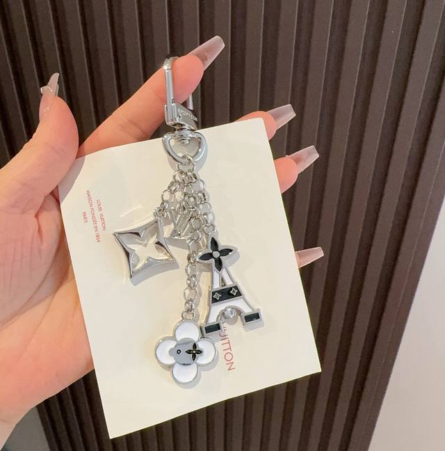 Lv包饰与钥匙扣 包包挂件 Lv 巴黎铁塔精巧链条四叶草铭牌装饰，与小号尖瓣 Monogram 花卉相映成趣，可为手袋增添华美一笔。