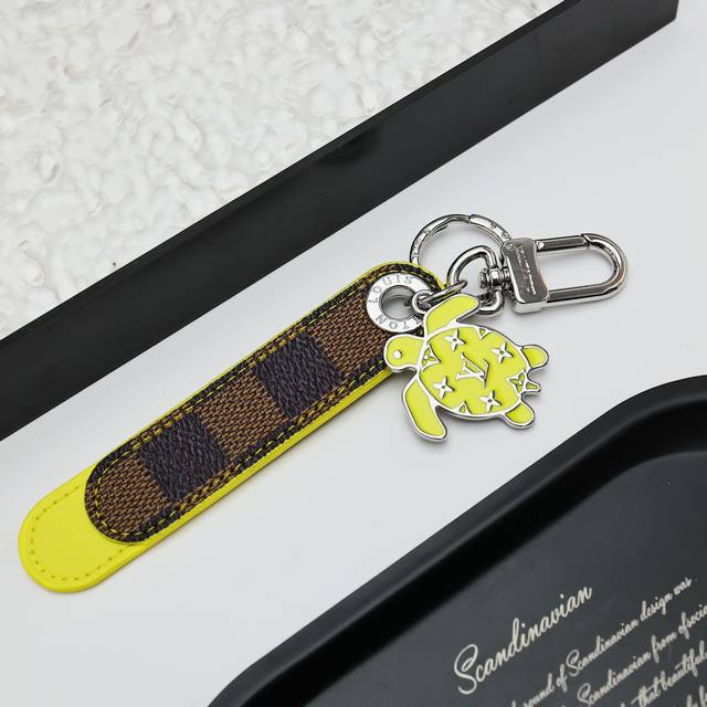 Dragonne Tab 包饰与钥匙 M02564 Dragonne Tab 包饰与钥匙扣出父亲节系列，以缤纷笔触成就又一赠礼佳选。圆润 Monogram 长短