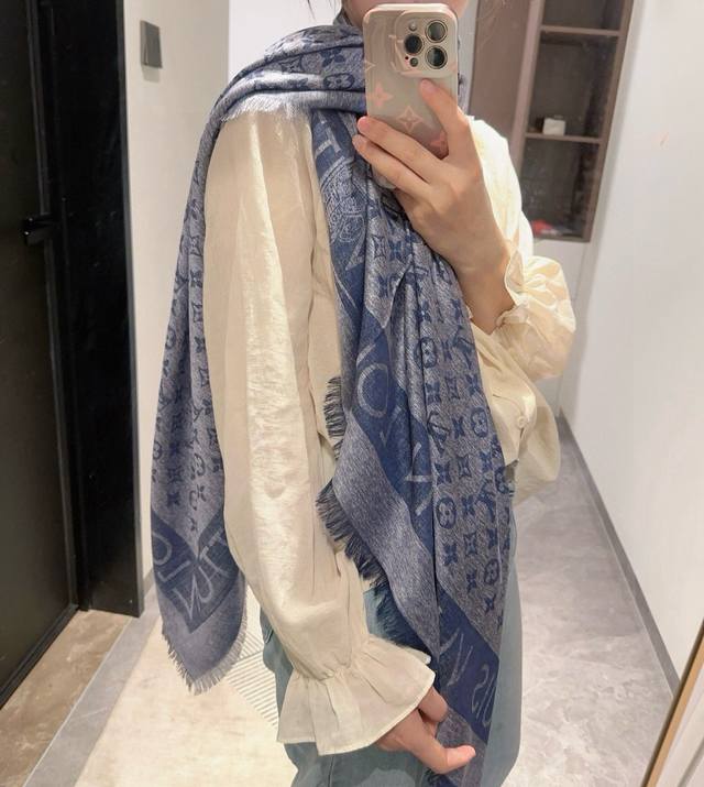 L V 新款披肩，仿佛挚爱牛仔裤经过时间洗礼后的别致纹理。华美丝毛混纺裁出大幅尺寸，带来多种造型可能。技术重新演绎Monogram图案。质地柔软而又温暖，带来令