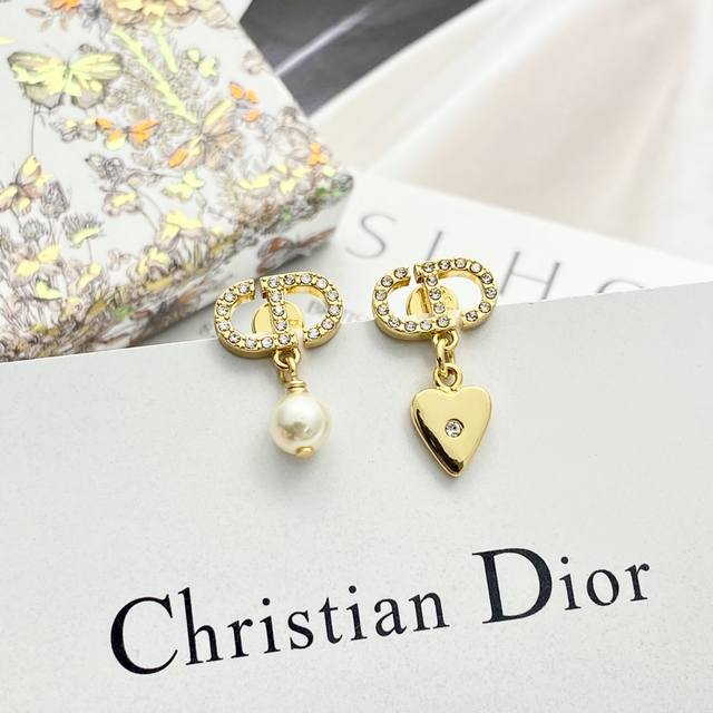 Dior耳钉热销款火爆上新 迪奥不对称爱心珍珠耳钉 采用金色饰面金属精心制作，不对称设计别具一格！水钻Cd吊坠爱心一侧搭配白色树脂珠 每一个都是经典元素！精致小