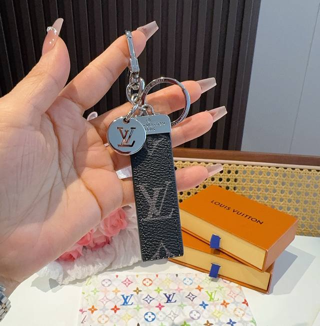 Lv钥匙扣 车钥匙扣 挂件 借鉴旅行袋中的钥匙扣设计，可满足各种时尚品味的实用配饰。新版Monogram Eclipse搭配银色Lv字母饰件，凸显时尚个性
