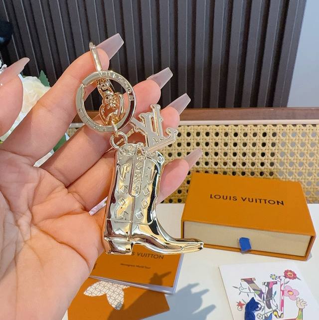 Lv钥匙扣 靴子挂件车钥匙挂饰，品牌经典标识巧妙嵌入链环之间。Lv字母装饰于一端优雅垂坠，弹簧扣实现轻松固定，为裤装或手袋注入潮流锋芒。