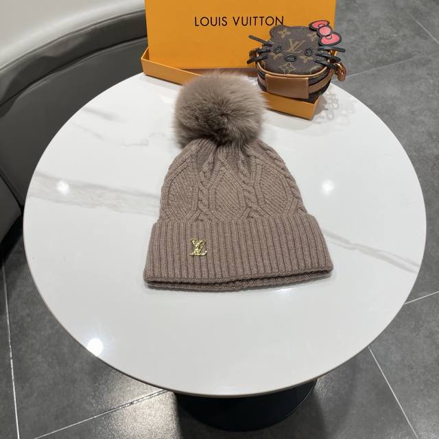 毛线帽经典麻花编织设计，帽身配有金色Lv标志。配狐狸毛球帽子采用优质羊毛+兔毛针织面料，保暖舒适，帽顶配有同色系毛球装饰，时尚大方。 帽子细节： - 经典麻花编