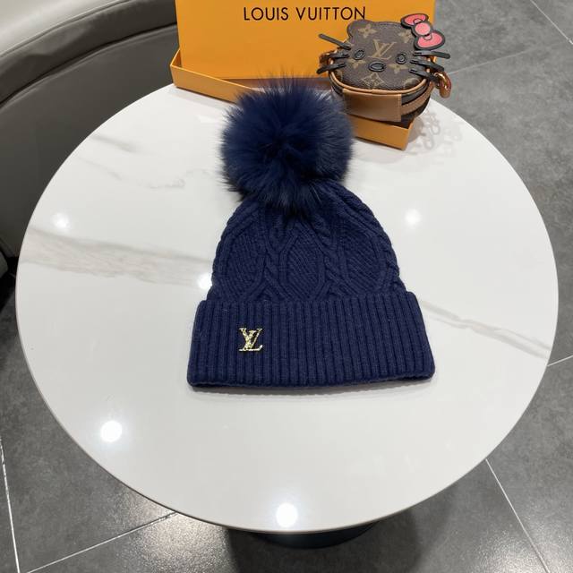 毛线帽经典麻花编织设计，帽身配有金色Lv标志。配狐狸毛球帽子采用优质羊毛+兔毛针织面料，保暖舒适，帽顶配有同色系毛球装饰，时尚大方。 帽子细节： - 经典麻花编