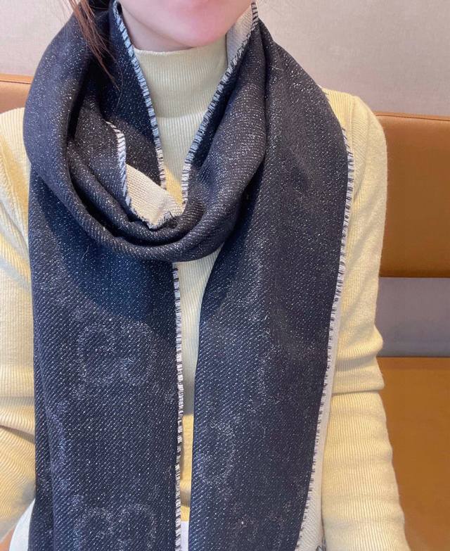 Gg品牌标志性元素不断推出妙趣横生的设计，以现代手法令经典单品呈现出时光沉淀的优雅美感。别致的Gg图案以提花细节的形式呈现在这款黑色和米色羊毛围巾上，饰以流苏滚