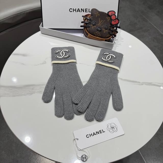 Chanel香奈儿针织手套，黑色配米白色边框，经典双C标志设计。手套采用优质针织面料，柔软舒适，保暖性好。均码设计，男女通用。手套上有品牌Logo刺绣，简约大气